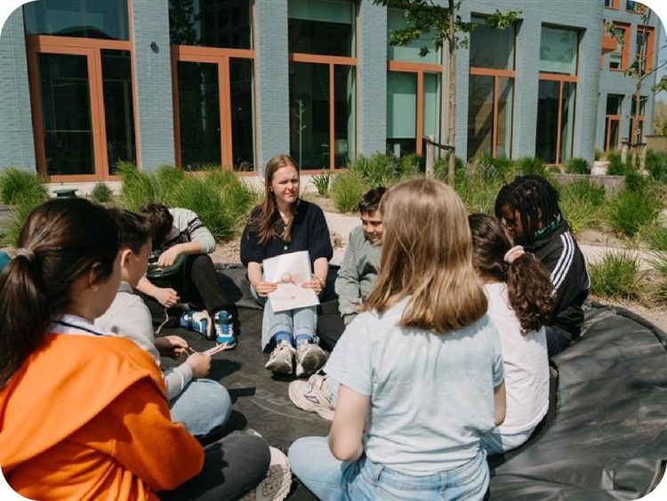 Kinderen zitten in een kring in de groene buitenruimte van een Upgrade Estate-project tijdens een activiteit van Upgrade Charity.