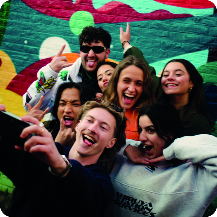 Een diverse groep jongeren neemt een enthousiaste groepsselfie — de sociale impact van Upgrade Estate in beeld.