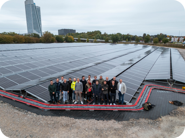 Een foto van medewerkers met het zonnepanelenpark van Upgrade Estate op The Loop in Gent. 
